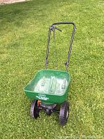 Front view of green Scotts Turf Builder 23-lb push broadcast spreader showing hopper, wheels and handle.