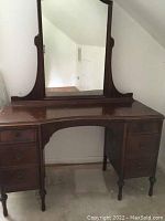 Front view of vintage wooden vanity with attached mirror showing overall condition and structure