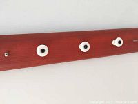 Close-up of 3 white ceramic knobs on a reddish-brown wooden wall rack, showing the material and finishes.