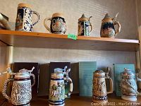 Eight decorative beer steins displayed on two wooden shelves, showing variety in design and lid types
