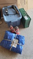 Overview of the camp stove, lanterns, tarp, and other camping items placed around a plastic bin.