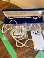 Freshwater pearl necklace and multiple pearl bracelets displayed on a table.