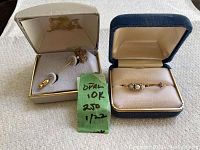 Overview of two jewelry boxes showing stick pin brooch in one and opal bar ring in the other, plus green karat note