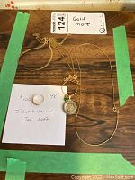 Overview of ring and three gold-tone necklaces on wood surface