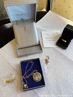 Overview of lot showing cross pendant in Peoples box, ring in black box, locket in blue box and loose chain pieces