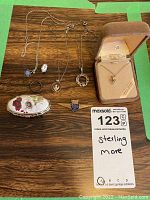 Full lot showing all pieces of sterling silver jewelry including necklaces, brooches, ring, pendant, and a display box with a heart pendant