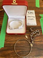 Grouped jewelry items on wooden surface with jewelry box. Includes bracelets, ring, and bangle bracelet.