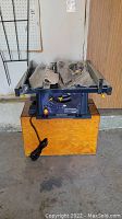 Mastercraft 10 inch table saw with power cord, accessories on top and wood storage box underneath.