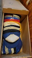 Box of assorted vintage baseball hats showing variety in colors including yellow, white, blue, and red