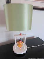 Full view of lamp showing green lampshade and white wooden base with swing figure