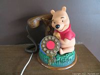 Front view of Winnie the Pooh phone showing Pooh figure, rotary dial, and tree branch handset.