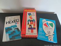 Top view of three vintage puzzle game boxes: Hexed Hi-Q, Blockhead, Perfect Circle.