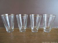 Set of four clear vintage glasses with gold rims and atomic starburst designs.