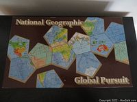 Top-down view of the game box showing the unique geometric world map design on the lid, brown background, and the text 'National Geographic Global Pursuit'.
