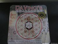 Front view of the sealed DaVinci's Challenge game box showing the circular Flower of Life design and Da Vinci portrait sketch.