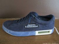 Side view of the blue sneaker-shaped phone with Sports Illustrated logo and LCD screen on the sole
