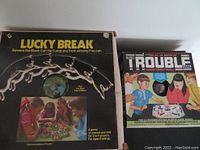 Photo showing the boxes of the 1975 Lucky Break and 1965 Trouble board games with original artwork and branding.