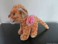 Photo showing left side profile of plush lion with rose on shoulder and Steiff ear tag