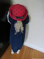 Full view of the vintage Time Out doll from the back showing the velvety dress, curly blonde ponytail, and red paisley hat with brown bow.
