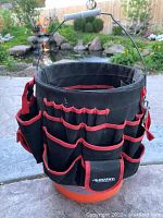Full front view of Husky tool holder bucket with multiple exterior pockets and handle.