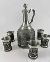 Main group photo of the vintage pewter decanter and five shot glasses with relief designs and German verse.