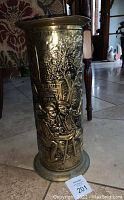 Full view of antique brass umbrella stand showing embossed scene of men sitting at table outside building