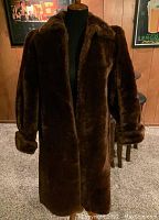 Front view of full length brown auburn genuine mouton fur coat on dress form showing coat with full cuffed sleeves and collar.