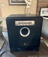 Front view of Yamaha black subwoofer with control knobs and front bass port.