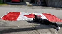Full spread of flag laid out on pavement with person for scale