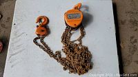 Full view of the orange ROK 2 ton chain hoist showing top hook, chain, and lifting hook on table surface