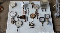 Wide view showing all gauges, thermometers, and meters on a white table, metal, glass, and wired items visible
