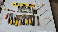 Full overview of all included tools arranged on white surface showing levels, scrapers, screwdriver, tape measure, and folding ruler