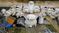 Wide view of entire concrete wall sculpture showing floral and leaf motifs and central decorative face.