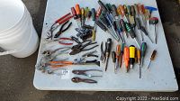 Wide shot of table with bucket and assorted screwdrivers, pliers, and drill bits spread out