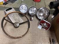 Overall view of all items including steering wheel and various car lights on a carpeted surface.