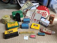 Overview of all vintage tins, first aid kit, metal signs, and boxes arranged on carpeted floor.