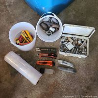 Full content photo displaying wrench sockets, utility knives, plastic wrap roll, and white metal tin with sockets.
