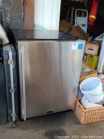 Front closed view of stainless steel Marvel mini fridge showing vertical handle and brand sticker.