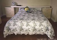 Full view of bed frame with connected nightstands, floral bedspread, mattress not included, room setting.