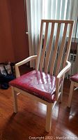 Light wood armchair with vertical slat backrest and red plastic-covered seat