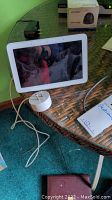 Google Nest Hub smart display showing screen and power adapter on table.