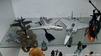 Nine model airplanes arranged on shelf with brass elephant figurine nearby