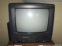 Front view of GoldStar CRT TV showing screen, VHS slot, and control buttons.