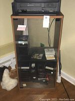 Sony wooden media cabinet with glass door, showing full front view and interior with one glass shelf. Cabinet measures 18 1/2 x 15 3/8 x 37 1/2 inches. Contents inside the cabinet are not included.
