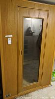 Front view of Soft Heat sauna room with a wooden frame and glass door panel showing interior room reflection.