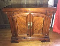 Front view of wooden side table showing double cabinet doors and surface with scratches and wear.