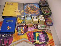 Overview showing binders, tin boxes, loose card stacks, poster and play mat