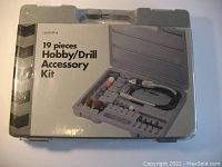 Closed plastic gray carrying case showing 19 piece hobby drill accessory kit label and partial plastic wrap.