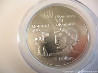 Reverse side of the 1974 Canadian $5 silver coin displaying athlete with torch and Olympic inscriptions