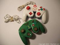 Photo of white Toad-themed and green Zelda-themed Wii U wired fight pads with cables wrapped. Visible button layouts and analog sticks.